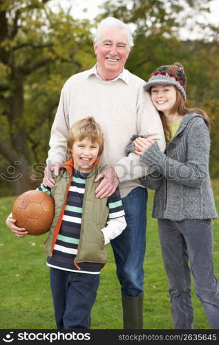 Grandfather With Grandchildren Holding Football Outside