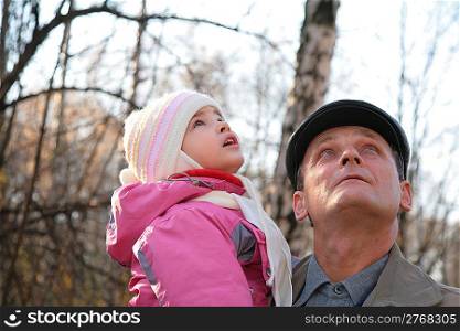 Grandfather with granddaughter on hands outdoor look upward