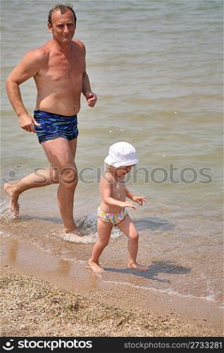 Grandfather with granddaughter run as to beach