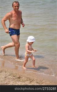 Grandfather with granddaughter run as to beach