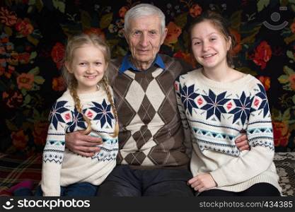 grandfather with granddaughters are sitting in the rural house
