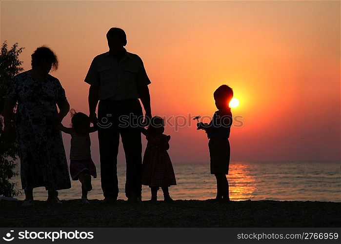 Grandfather with grandmother and the children against the background of sunset