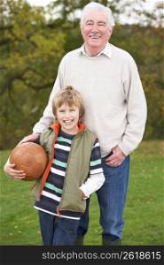 Grandfather With Grandson Holding Football Outside