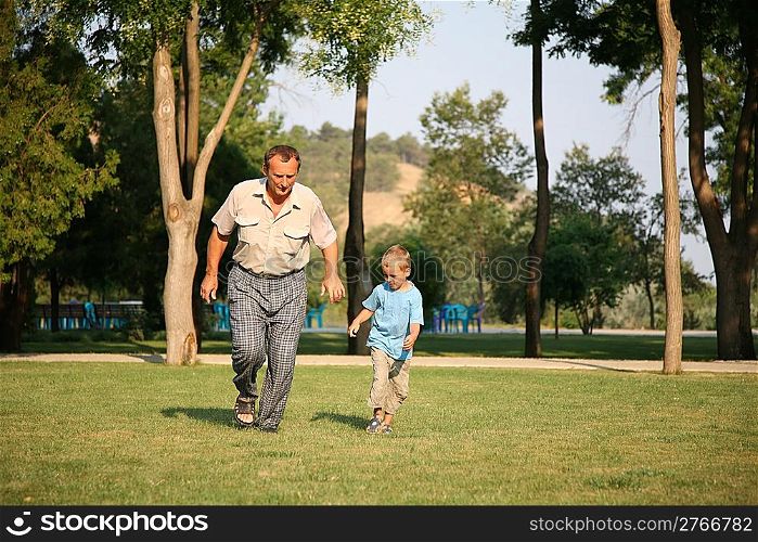 Grandfather with grandson run as to lawn