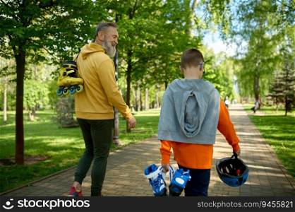 Grandfather with grandson walking in park preparing roller-skates and helmet or extreme racing. Grandpa with grandson walking in park going to roller-skate