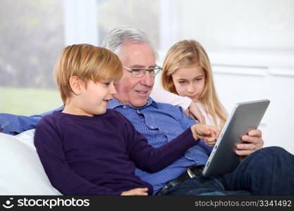 Grandfather with kids using electronic tab