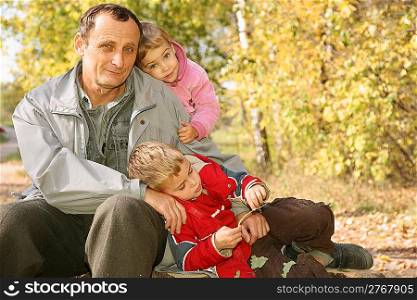 grandfather with the grandson and the granddaughter in the park in autumn