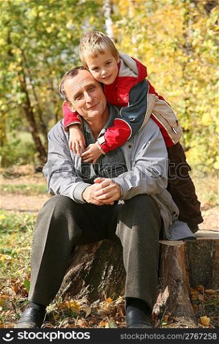 grandfather with the grandson sit in park in autumn