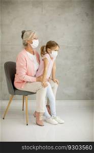 Grandmother and cute little granddaughter wearing a respiratory masks