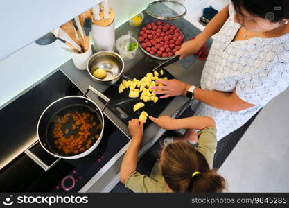 Grandmother and granddaughter are preparing soup at home at the stove.. Grandmother and granddaughter are preparing soup.
