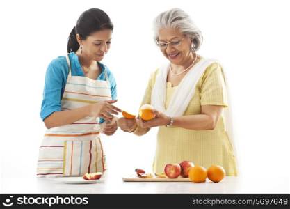 Grandmother and granddaughter cutting fruits