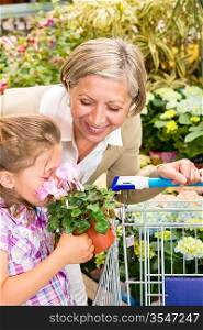 Grandmother and granddaughter holding pink potted flower at garden centre