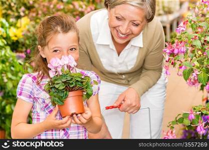 Grandmother and granddaughter holding purple potted cyclamen at garden centre