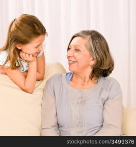 Grandmother and granddaughter look at each other relax on sofa