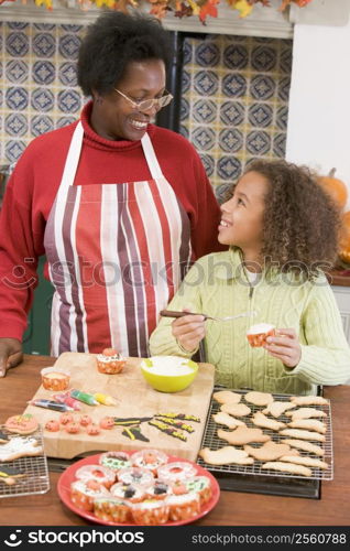 Grandmother and granddaughter making Halloween treats and smiling