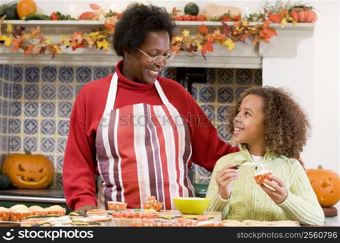 Grandmother and granddaughter making Halloween treats and smiling