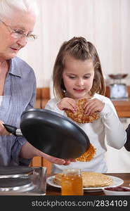 Grandmother and granddaughter making pancakes