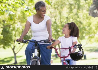 Grandmother and granddaughter on bikes outdoors smiling