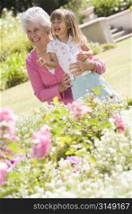 Grandmother and granddaughter outdoors in garden smiling