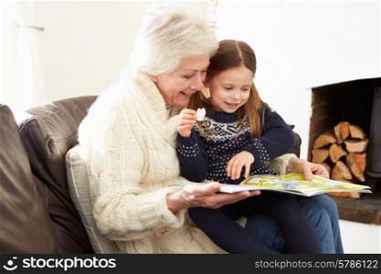 Grandmother And Granddaughter Reading Book At Home Together