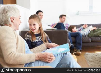 Grandmother And Granddaughter Reading Book At Home Together