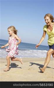 Grandmother And Granddaughter Running Along Beach