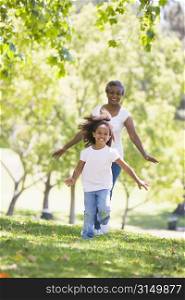 Grandmother and granddaughter running in park and smiling