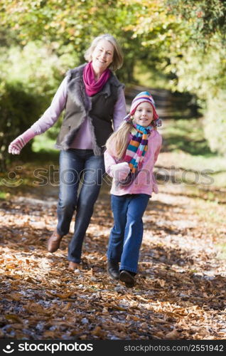 Grandmother and granddaughter running outdoors in park and smiling