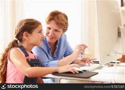 Grandmother And Granddaughter Using Computer At Home