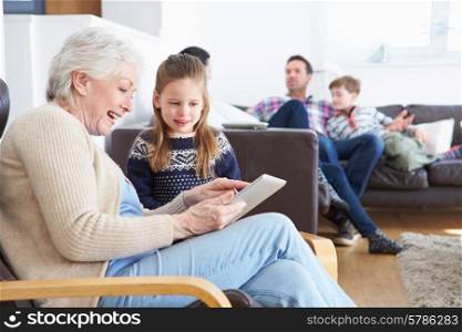 Grandmother And Granddaughter Using Digital Tablet Together