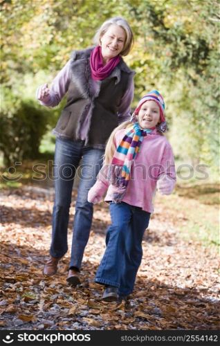 Grandmother and granddaughter walking on path outdoors smiling (selective focus)