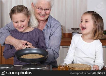 grandmother and granddaughters making pancakes
