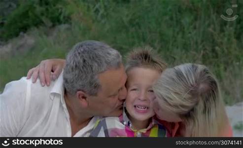 Grandmother and grandfather kissing grandson in both cheeks to express the love. Happy to have a grandchild