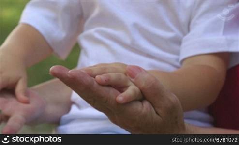 Grandmother and grandson holding hands close-up