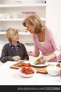Grandmother And Grandson Making Sandwich In Kitchen