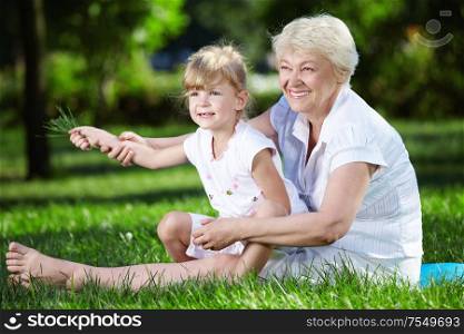 Grandmother and her granddaughter on the grass in the park