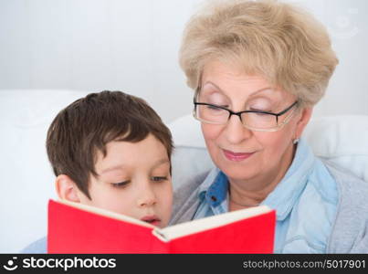 Grandmother and little boy reading book happy together at home