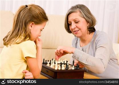 Grandmother and young girl playing chess together at home