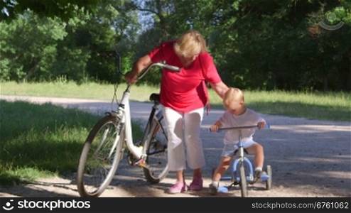Grandmother assisting grandson to ride a bicycle in the park