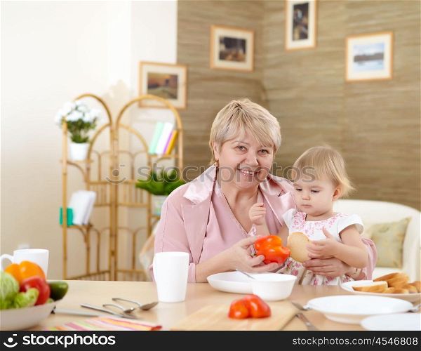 grandmother feeding her little baby granddaughter at home