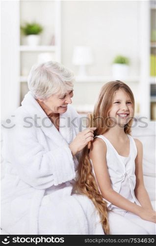 Grandmother granddaughter combs her hair at home