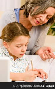 Grandmother help granddaughter doing school homework together at home