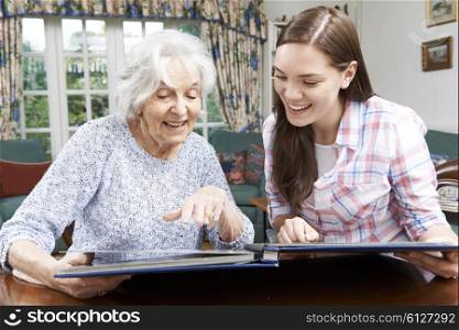 Grandmother Looking At Photo Album With Teenage Granddaughter