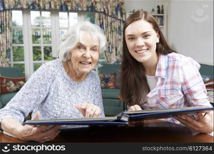 Grandmother Looking At Photo Album With Teenage Granddaughter