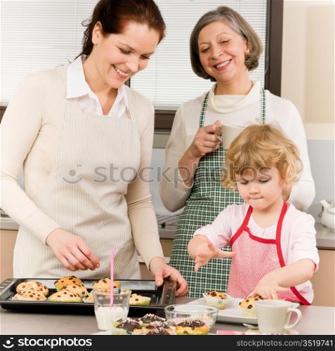 Grandmother, mother and child girl making cupcakes in kitchen