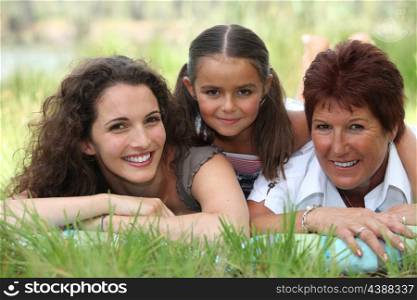 Grandmother, mother and daughter lying in the grass