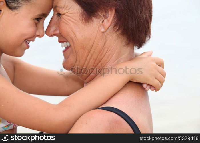 Grandmother nose to nose with her granddaughter on the beach