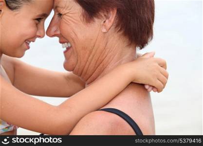 Grandmother nose to nose with her granddaughter on the beach