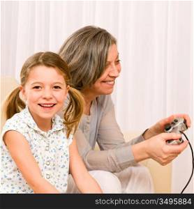 Grandmother play computer game with enthusiastic young girl have fun smiling