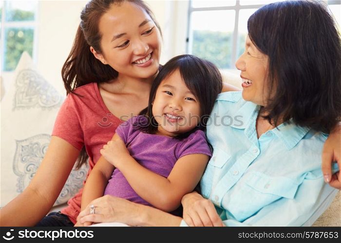 Grandmother Playing On Sofa With Granddaughter And Daughter